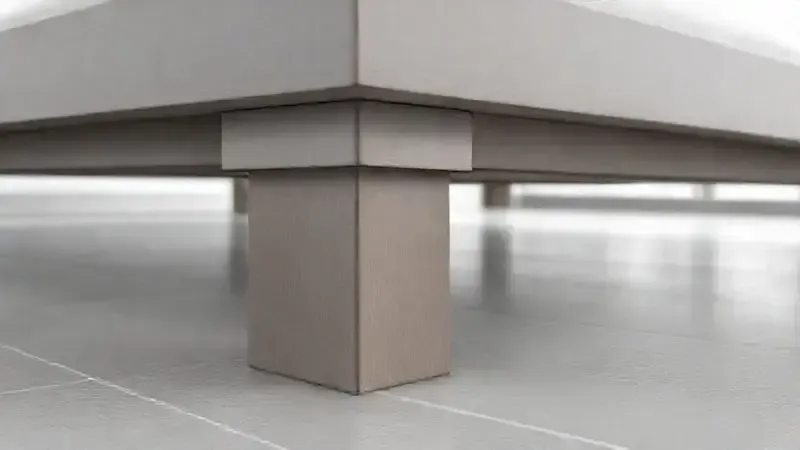 Renderização 3D em close-up da base e dos pés de uma cama, transmitindo a ideia de estabilidade, robustez e segurança estrutural.